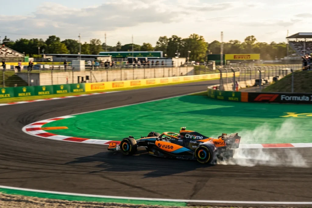 Monoplaza de Fórmula 1 color papaya en curva de circuito con piloto al volante
