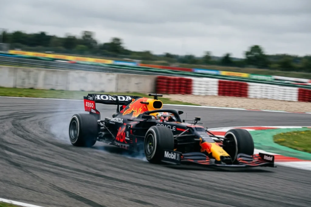 Monoplaza de Fórmula 1 en acción en pista con casco de piloto visible en cockpit